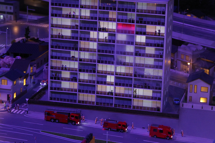 「火事だ！」 マンションの一室から煙が上がり、サイレンを鳴らして消防車が駆けつける。画面にはないが、次いで救急車も到着、けが人を病院に搬送する。このほかにも、ギャラリーを驚かせる仕掛けがたっぷり。