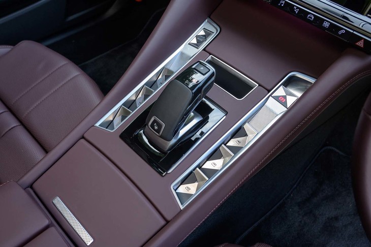 変速機はアイシン製の8段AT「e-EAT8」。シフトセレクターのまわりにはギヨシェ彫り（風）のウィンドウオープナーなどが整然と並べられる。