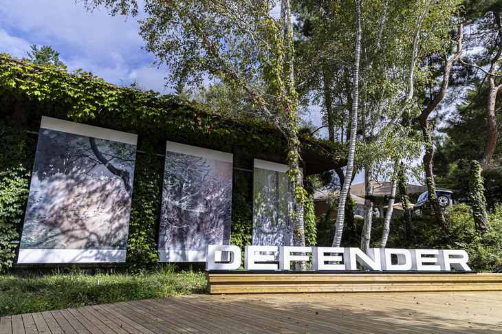 「DEFENDER」ロゴのオブジェが置かれたMMoPのウッドデッキ。来場者がどこでどのように過ごすかは自由。参加当日は週末ということもあり、家族連れの姿が多く見受けられた。