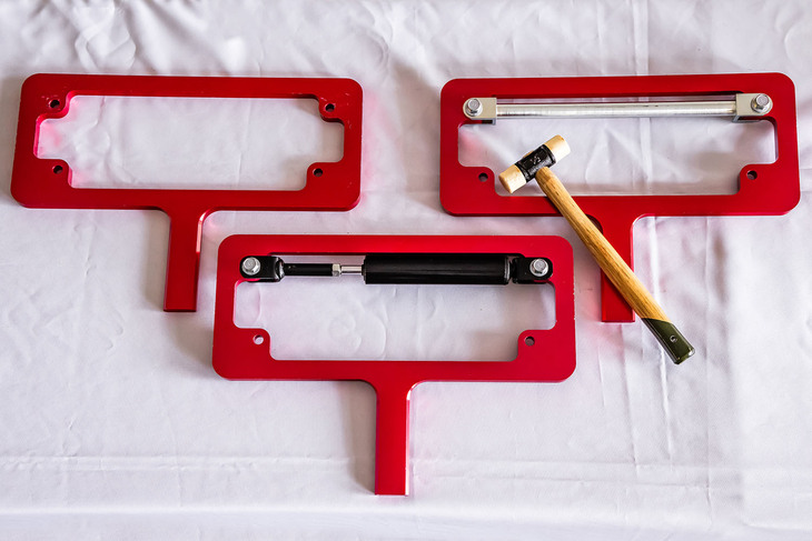 「パフォーマンスダンパー」の効果をわかりやすくテストできるように用意された金属のフレーム。左上が標準の車体を、右上がストラットタワーバー装着を、下がパフォーマンスダンパー装着を模した状態。手に持った赤いフレーム部分をハンマーでたたくと、「パフォーマンスダンパー」を装着したものは音が鈍く、瞬時に振動がおさまった。