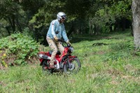 草の生い茂るオフロードを走る筆者。この程度のフィールドはお手のもの。車体色は写真の「グローイングレッド」のほか、アースカラーの「マットフレスコブラウン」も選べる。
