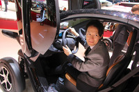 プレスデイの最中にも、乗ってみる人が多数みられた。そこでついでに筆者もの図。ヘルメット要らずなのは、従来のバイク派に対する「トゥイジー」の大きなセールポイントである。