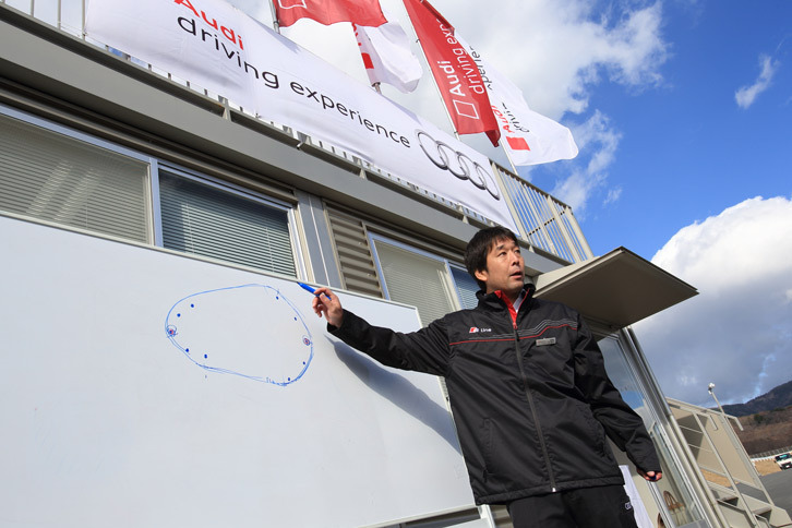 ステアリングワークの練習は、Rの異なる2つのコーナーを組み合わせた、小さなオーバルコースで行う。写真はコースについて説明するインストラクターの井尻 薫（いじりかおる）さん。