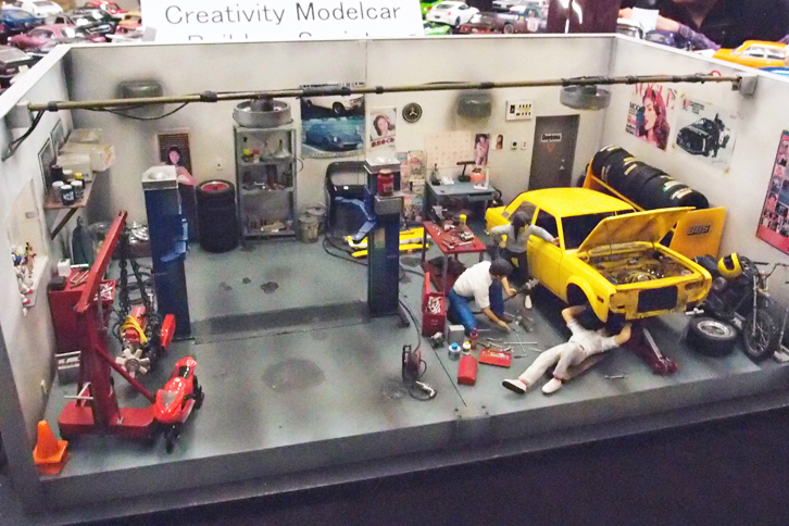 レベル／ユニオン製1/25「ダットサン510」（「ブルーバード」2ドアセダン）を使ったガレージ（ショップ）のジオラマ。壁に貼られた色あせたポスター、スタンドに並べられた新品タイヤ、棚に載せられた、ホコリの積もったダンボール箱など、ものすごく凝っていた。