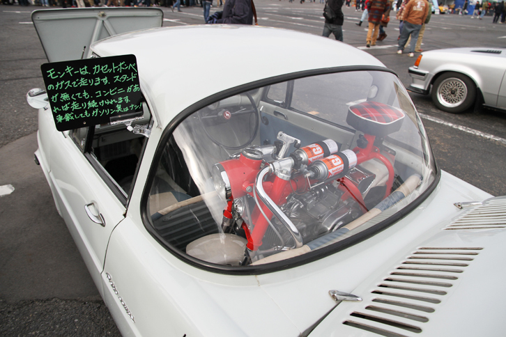 1965年「マツダR360クーペ」のリアトレーに、カセットボンベのガスで走行できるよう改造された「ホンダ・モンキー」が積まれていた。