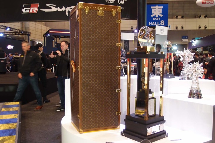 ルマン24時間の優勝トロフィー。会場に展示されているのは複製ではない本物で、奥（中央）に見えるルイ・ヴィトン製の大きなトランクがその専用ケース。