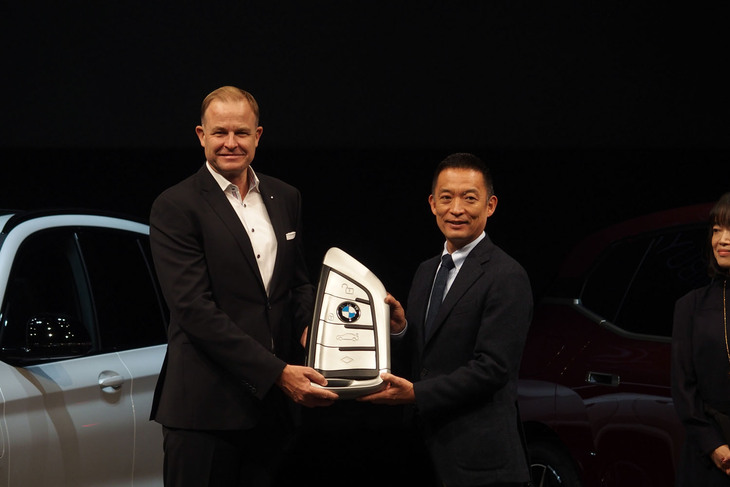 BMWジャパンは、渋谷区に1年間「BMW iX」を貸与すると発表。BMWジャパンの代表取締役社長クリスチャン・ヴィードマン氏（左）から渋谷区長の長谷部健氏（右）にキーの贈呈が行われた。