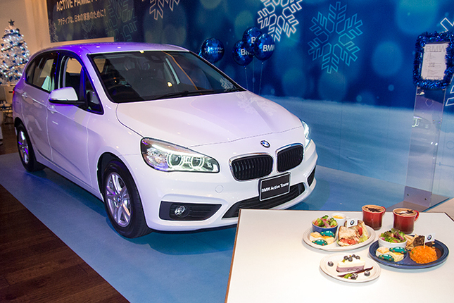「BMW 218iアクティブツアラー」とカフェのフードメニュー。