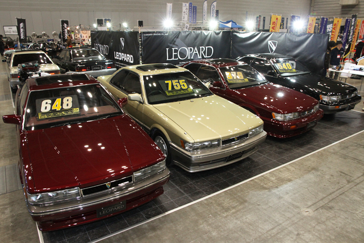 このイベントではおなじみの、2代目「日産レパード」（F31）の専門店であるカーショップフレンドのブース。TVドラマ『あぶない刑事』の劇用車と同じシャンパンゴールドに塗られた「アルティマ」（左から2台目）は、3リッターV6 DOHCのVG30DEを積んだ前期型の最高級グレードである。価格はご覧のとおり755万円。