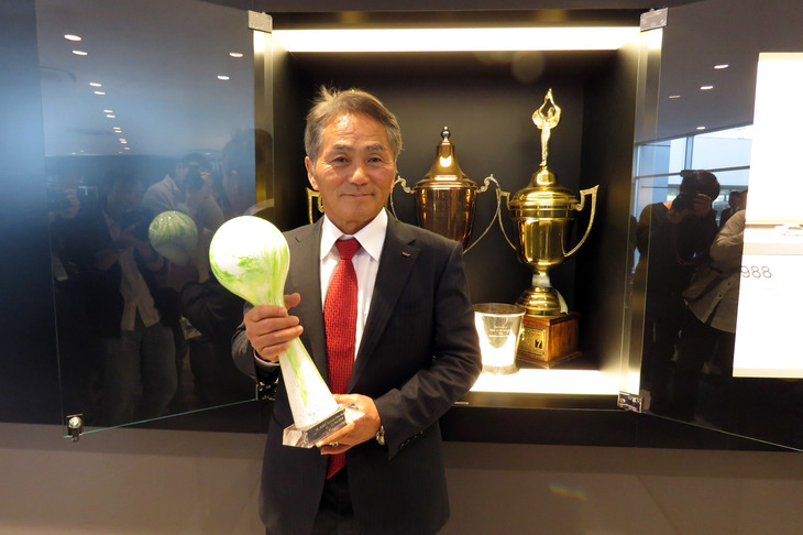 下段のショーウィンドウに展示されているトロフィーは、係員に言えば手にとって記念撮影が可能とのこと。写真は2018年のニュルブルクリンク24時間レース SP3Tクラスの優勝トロフィーと辰己総監督。