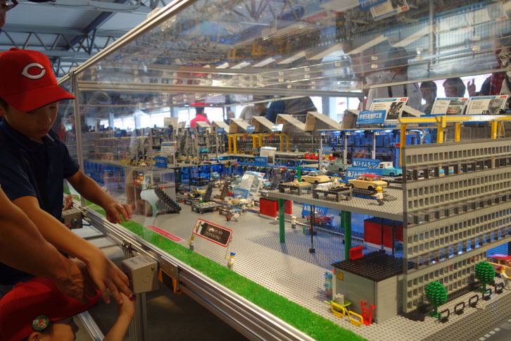 【工場模型展示】こちらは裏側。カープ帽の男の子が押しているボタンで、コンベヤーが動く仕掛けになっている。