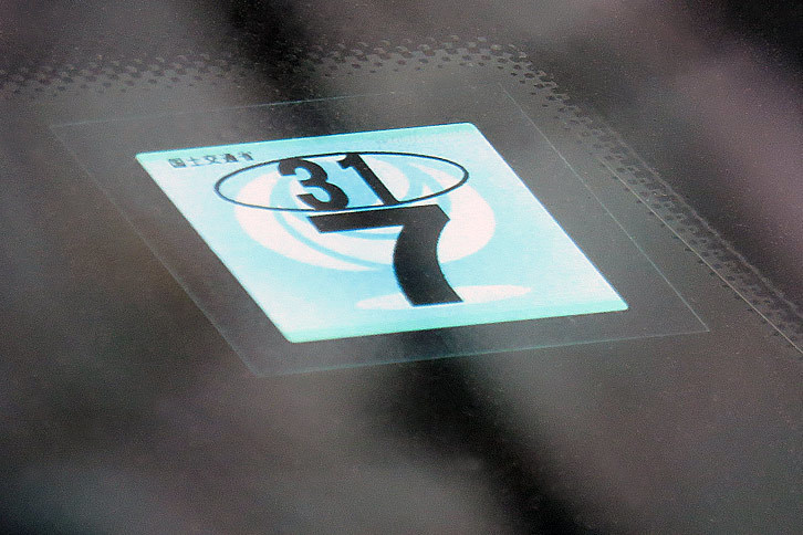車検シールこと「検査標章」には、でかい文字で月の、小さい文字で和暦の年が記載されている。ちなみにこちらは古いデザインの検査標章。2017年1月からは、より表記がシンプルで、ひとまわりサイズも大きな検査標章が採用されている。