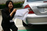 女性が手にしている白いハンカチは、メルセデス・ベンツ E320CDIの排気管をふさぐように被せておいたもの。白さが失われていないことがアピールされた。