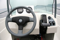 「テルヒ・ビッグファン」のコクピット。正面に位置するデジタル表示のメーターは左がスピード、右がタコメーターで、「HONDA」ロゴ入りの純正アクセサリー。ステアリング右のスロットルレバーは、この位置がニュートラル（中立）で、上に倒していくと前進、下に倒していくと後退する。レバー頭部左側にあるスイッチは、船外機の角度を変える（前傾・後傾）もの。
