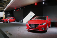 ステージ上に展示される「アクセラ」のセダン（奥）とハッチバック（手前）。
    