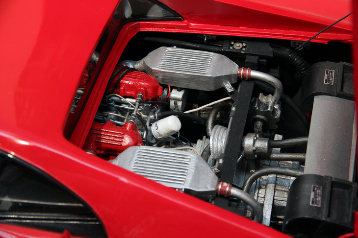 「288GTO」の2.9リッターV8 DOHCツインターボユニット。写真右端の上下に見えるプレートの文字が気になり、老眼の目を細めて必死に眺めていたら「適当に描いてるんだから、そんなとこまで見ないでくれよ！」と苦笑していた。
