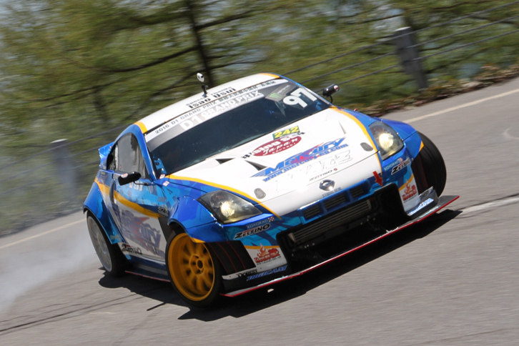 派手にタイヤスモークを上げながら、コーナーをドリフトで抜けていく2003年「日産フェアレディZ」（Z33）。