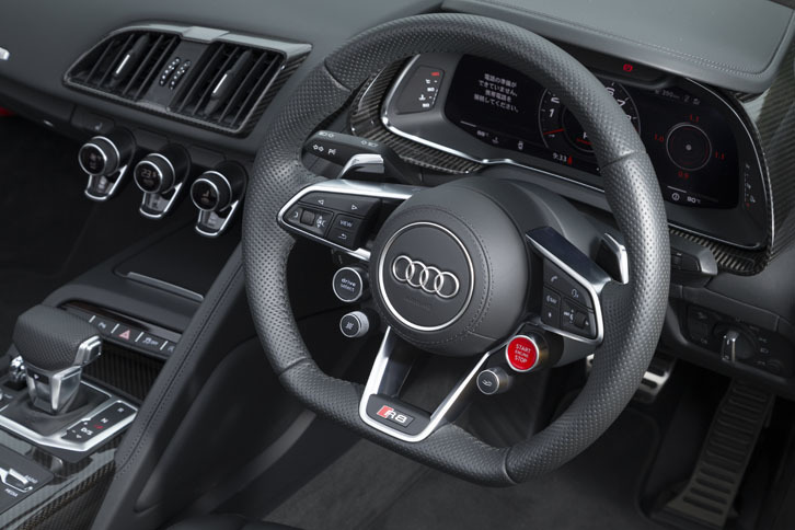 下端がフラットなデザインのステアリングホイール。センターの右下にはエンジンのスタートボタンが、左下には走行モードのセレクトボタンがレイアウトされる。