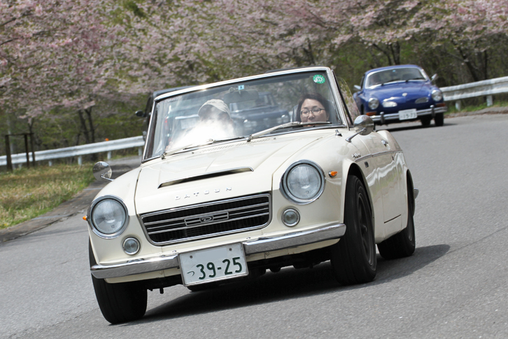 型式名SR311こと1969年「ダットサン・フェアレディ2000」。後ろに「フォルクスワーゲン・カルマンギア クーペ」が見える。