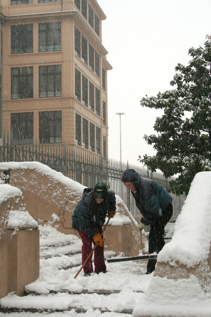 階段に積もった雪をのける関係者。