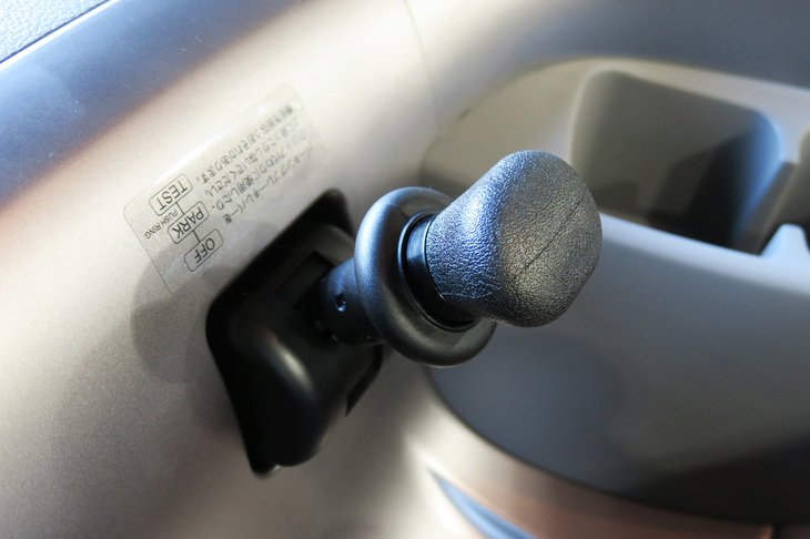 センターコンソールにキノコのように生えたパーキングブレーキのレバー。「クオンGW」にはブレーキホールド機能が備わっており、パーキングブレーキを解除してブレーキペダルをリリースしても、すぐにはクルマが動かないようになっている。