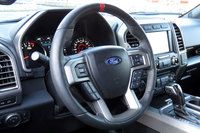 赤いセンターマークが目を引くステアリングホイール。「ラプター」にはステアリングの手応えを3段階で調整できるセレクト機能が付いている。……それにしても、最近のクルマってステアリングスイッチ多すぎませんか？