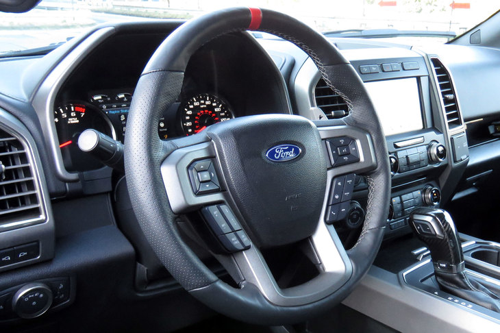 赤いセンターマークが目を引くステアリングホイール。「ラプター」にはステアリングの手応えを3段階で調整できるセレクト機能が付いている。……それにしても、最近のクルマってステアリングスイッチ多すぎませんか？