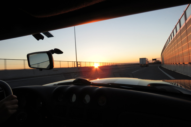 正面から昇る冬の太陽がまぶしい！ ちなみに、ダッシュボードの上にあるのは記者のサイフ。方々に2人分の手荷物をしまっていたら、あぶれてしまったのだ。