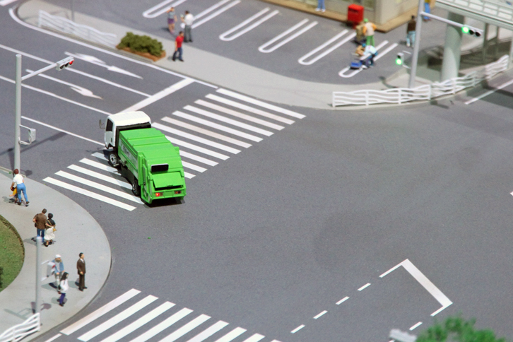 ジオラマの中で、交差点を左折していくゴミ収集車。走行は信号に従い、右左折時にはウインカーが点滅するようプログラムされている。