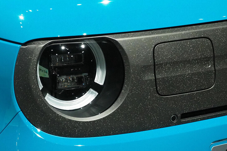 充電口を収めるフロントの装飾パネルには、バンパーのリサイクル素材を採用。通常なら除去する塗膜粉をあえて残すことで、独自の風合いを表現しているという。再生素材であることを隠さず、むしろ主張するところに、今という時代を感じる……。
