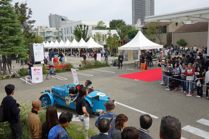 PC競技の会場へと向かう1932年式「MG Cタイプ モンテリ ミジェット」と、それを迎える観客。奥に見えるスタンプポイント（赤いカーペットが敷かれているエリア）では、FCAジャパンのティツィアナ・アランプレセ氏が通過車両にスタンプを押していた。