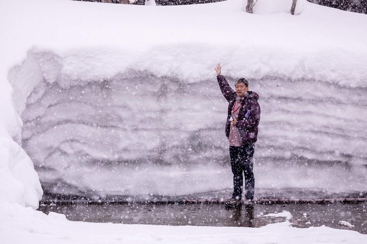成人男性（筆者）の背丈よりも積もった雪の壁。写真は肘折温泉の駐車場にて撮影した。