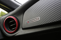 カーボン調のインストゥルメントパネル。助手席側の端には、専用のオーナメントが添えられる。赤いエアコン吹出し口も、専用装備の一つ。
    