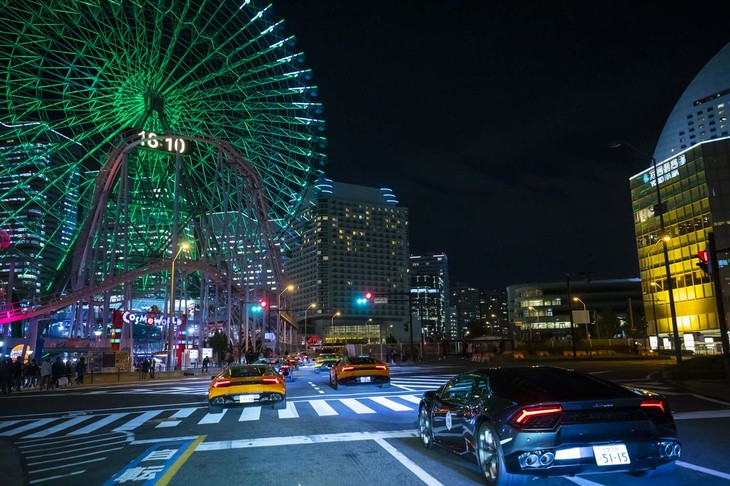 「よこはまコスモワールド」の大観覧車付近をパレードラン中の新旧ランボルギーニ。夕闇迫る横浜の街にいきなり現れ、そして模範的に走行する150台以上のランボルギーニに、道行く人々は驚いたもよう。手元のカメラなどで興奮しながら写真撮影をする人も。