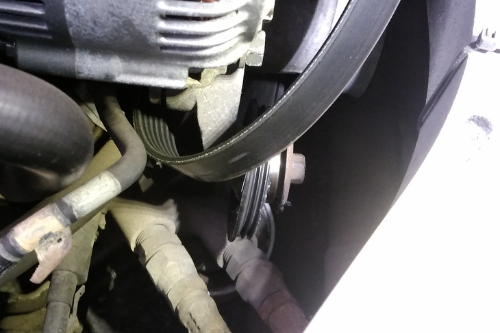 後日、コレクションズ本多氏より送られてきたエンジンルーム内の写真。ベルト、完全に外れとるやんけ！ おかしいなあ、自分で見たときは、かかっているように見えたんだけど……。ちなみに、奥の方に、今回のトラブルの原因となったテンションプーリー（だったもの）が写っている。