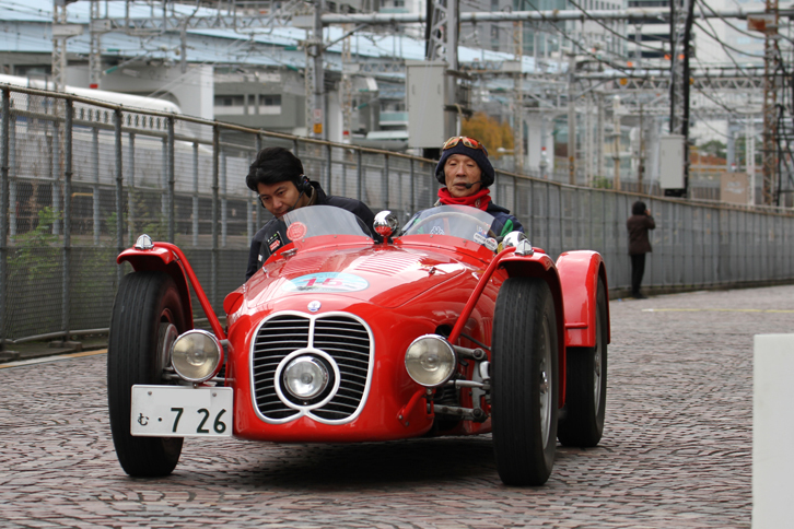 決められた区間をいかに指定時間に近いペースで走れるかを競う“PC競技”に臨む、1948年「マセラティA6G」。ドライバーは「ラ・フェスタ・ミッレミリア」の参加窓口であるヴェテランカークラブ東京の会長を務めるタレントの堺 正章氏。コドライバーが下を見ているのは、俗に“線踏み”と呼ばれるPC競技の、「線」こと路上に設置されたセンサーの位置を見きわめドライバーに指示するため。