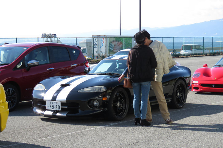 日なたぼっこ中のバイパーを前に語らうカップルの図。記者の脳内で、「見なよ、このチリのデカさ」「これだからアメ車はイヤなのよねえ」という仲むつまじい会話が自動再生される。