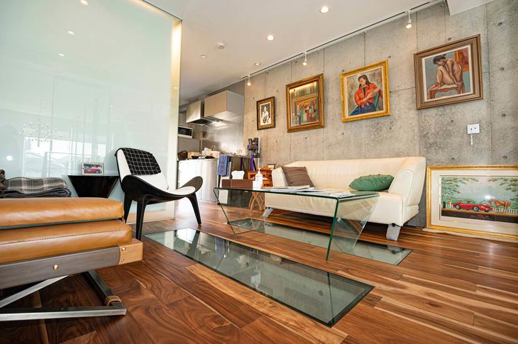 キッチン、食器棚、バスルーム、トイレも完備。フローリングに設けられた、階下の愛車を眺められる2カ所のガラスの窓は、クルマ好きにはたまらない“仕掛け”。壁にはお父さまが趣味で描かれた絵画が飾られている。