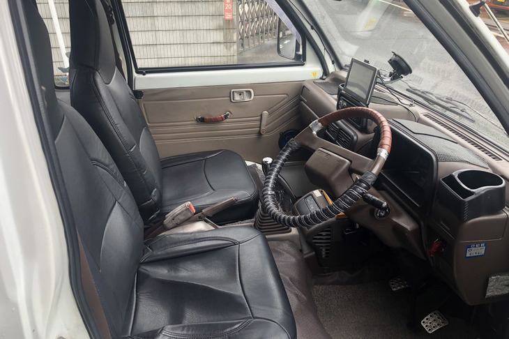 実車を見ずして購入し、納車された「ハイゼット トラック ジャンボ」のインテリア。車内に汚らしく残ったアルミテープがいい味わいだ。これは残そう……。シートにかぶせられた黒いカバーの下のシート本体はボロボロでした。