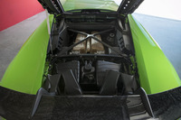 フォージドコンポジット製のエンジンフードを開けたところ。リアウイングの根元に左右2本、計4本のエアダクトが見える。中央の2本は常に開いた状態でエンジンルームの換気や排気冷却を行う。外側の2本はウイングのインナーチャンネルにつながっている。