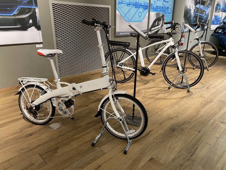 「フィアット500」のイメージを投影した電動アシスト自転車が並ぶ一角。手前のフォールディング式ミニサイクルは1490ユーロ（約19万円）。