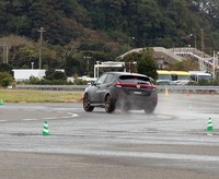 ぬれたテストコース上を旋回するテストカー。FFの普通の「リーフ」では外側に大きくはらむ速度でも、はるかに小さな回転半径でコーナリングできる。