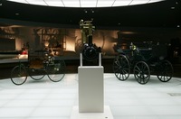 写真左がカール・ベンツの手になる最初のクルマ「パテント・モトールヴァーゲン」。右は馬車にエンジンを搭載した「ダイムラー・モトールクッツェ」。