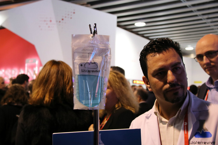 スペイン国王が会場に姿を現した直後、「点滴」を持った白衣の人物が！ 「すわ、事件か」と思いきや、水没したスマートフォンを特殊な液に漬けてよみがえらせる「ウオーターリバイブ」なるスタートアップ商品のデモだった。