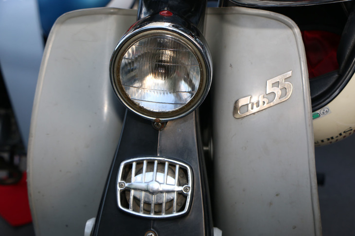 会場で出会った「カブ」たちのエンブレムを紹介。1961年に登場した「スーパーカブC105」。50ccエンジンをボアアップしたことを示す「55」のエンブレムが誇らしい。中央のグリルバッジも第1世代の特徴だ。