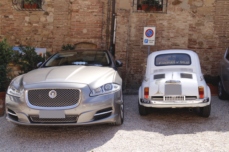 近くにはリストランテの店名が記された先代「フィアット500」（写真右）が。隣の「ジャガーXJ」がひときわ巨大に見える。