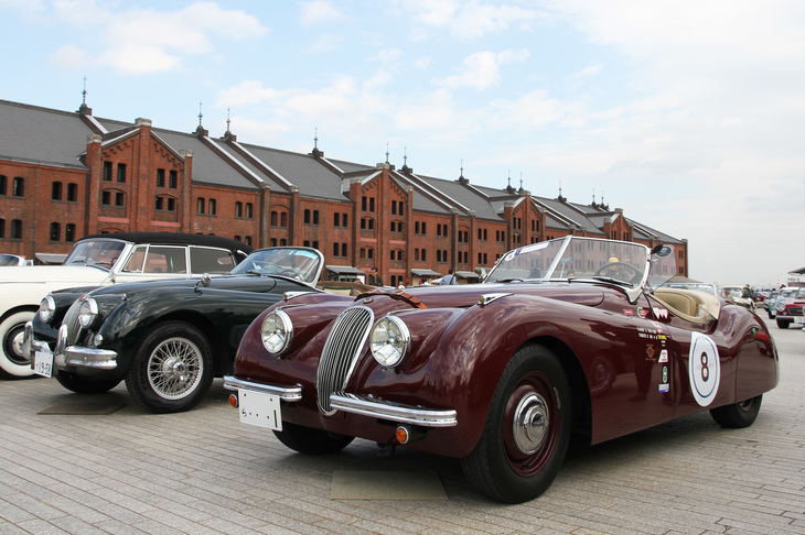 1948年に登場し、直6 DOHCのXKユニットによるハイパフォーマンスで今日へと続くジャガーのスポーツイメージを決定づけた「XK120ロードスター」（写真右）と、その後継モデルとなる「XK150ロードスター」（同左）。