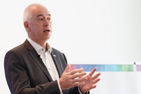 新社屋の竣工（しゅんこう）や横浜市都筑区との協業について説明するメッカー氏。今後も地域活性化にさらに貢献することで、「Invented for life」を体現する企業として成長を目指すと述べた。