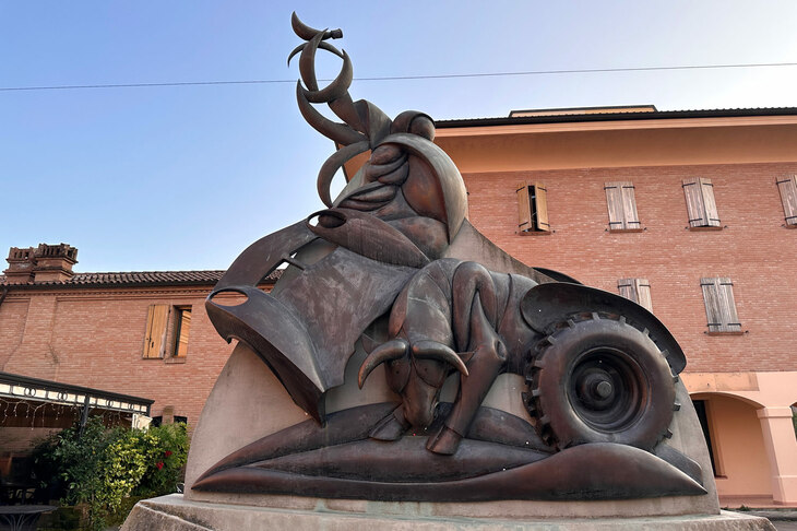 レナッツォ地区のフェルッチョ・ランボルギーニ広場で。彼にささげられた「実現性と天才」と名づけられた彫刻。牡牛（おうし）座であった彼にちなんだ闘牛、トラクターのタイヤに加え、スポーツカーの「ミウラ」を模したと思われる部分もみられる。サルヴァトーレ・アメリオ作。