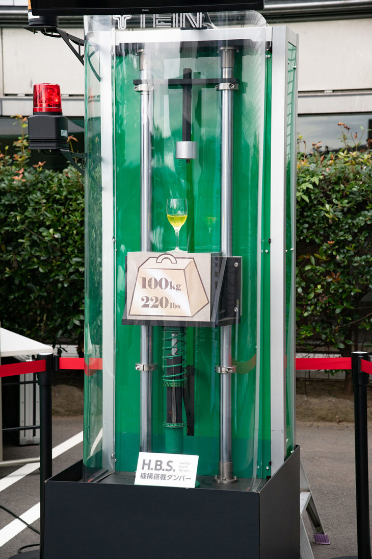 「エンデュラプロ」に100kgの重りを落下させるデモンストレーション。フルバンプしても重りを跳ね返さないので、グラス内の水が跳ねたりこぼれたりすることはない。